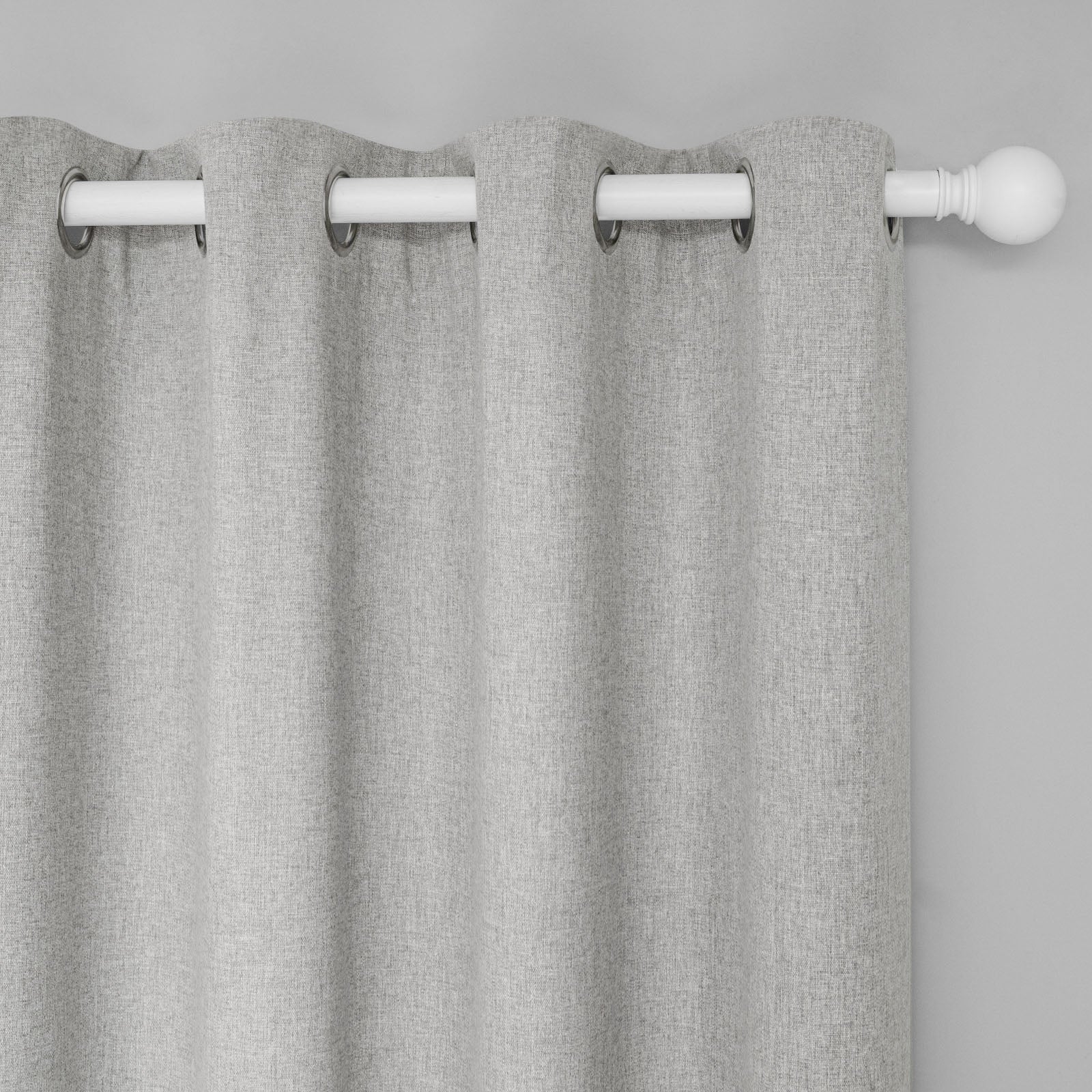 Close-up of soft grey cotton linen curtain, showcasing textured fabric and metal grommets on a white rod.