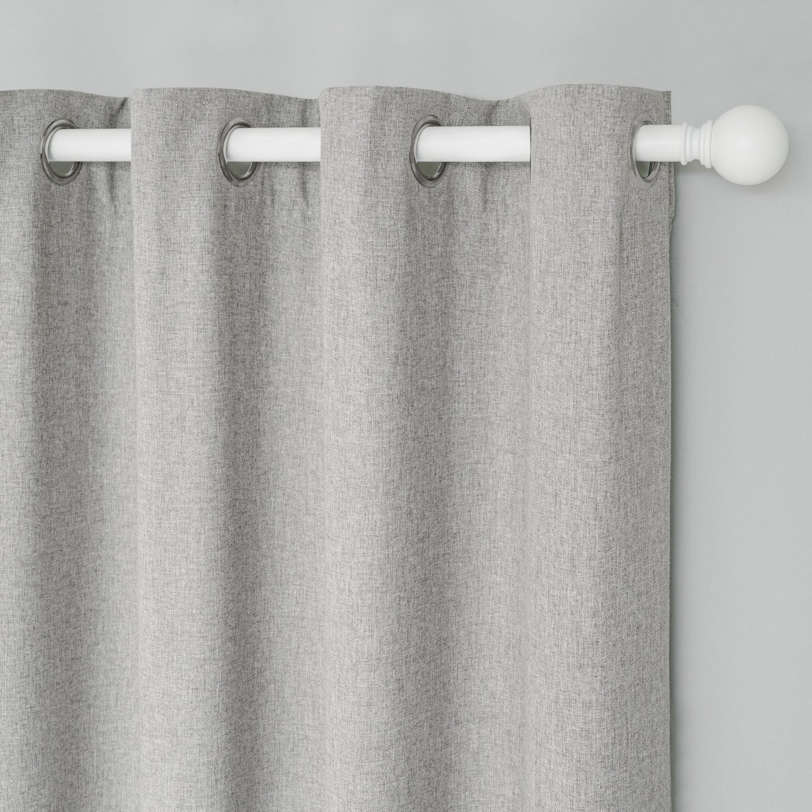 Close-up of soft light grey cotton linen curtain with grommet top, showing fabric texture and white curtain rod.