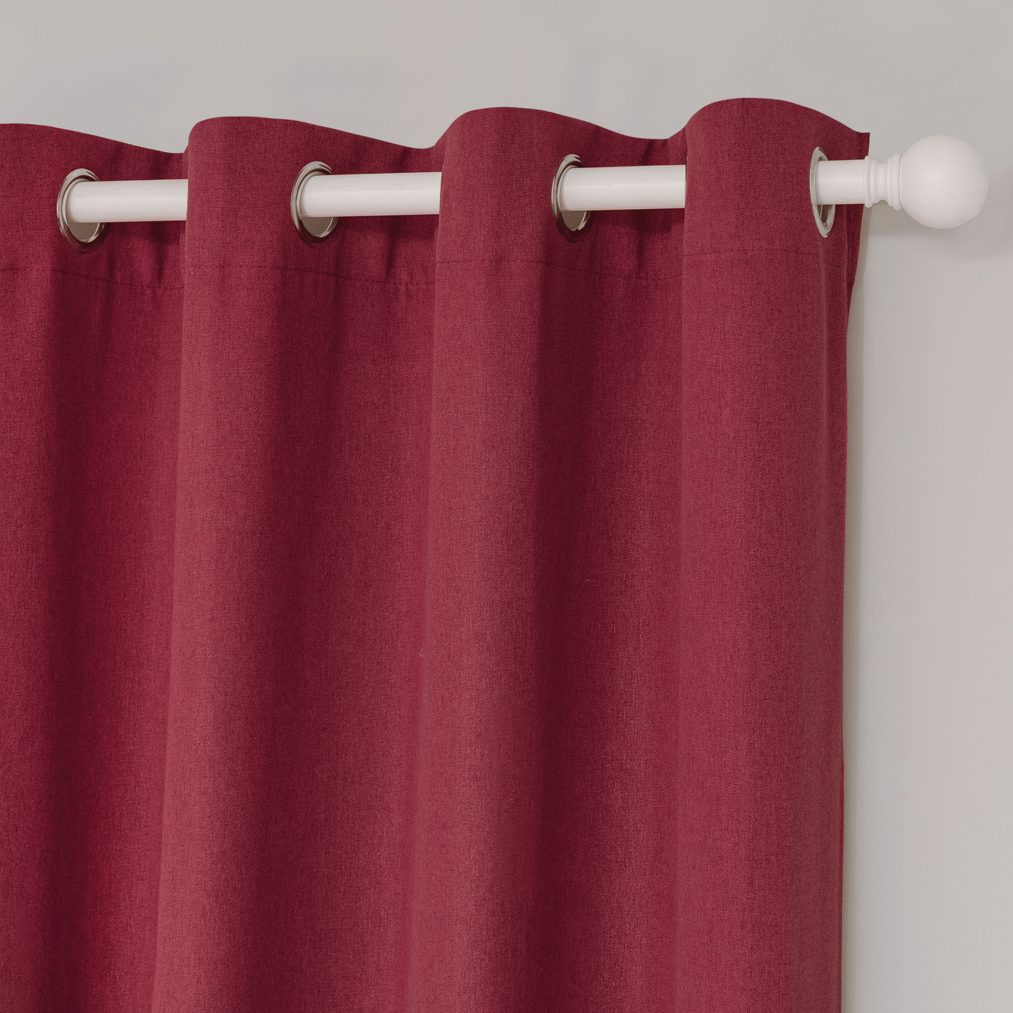 Detailed close-up of a deep red soft cotton linen curtain, highlighting the grommet top on a white curtain rod.