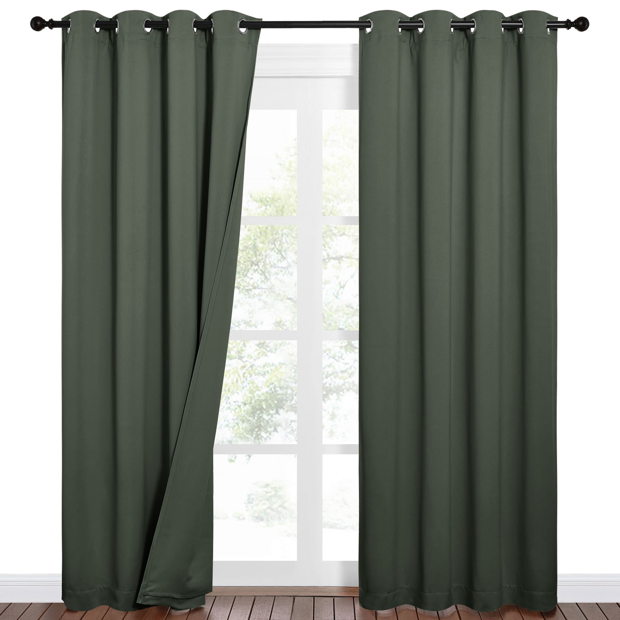 Pair of dark green sound barrier blackout curtains with grommets, one partially open over a window showing outdoor trees.