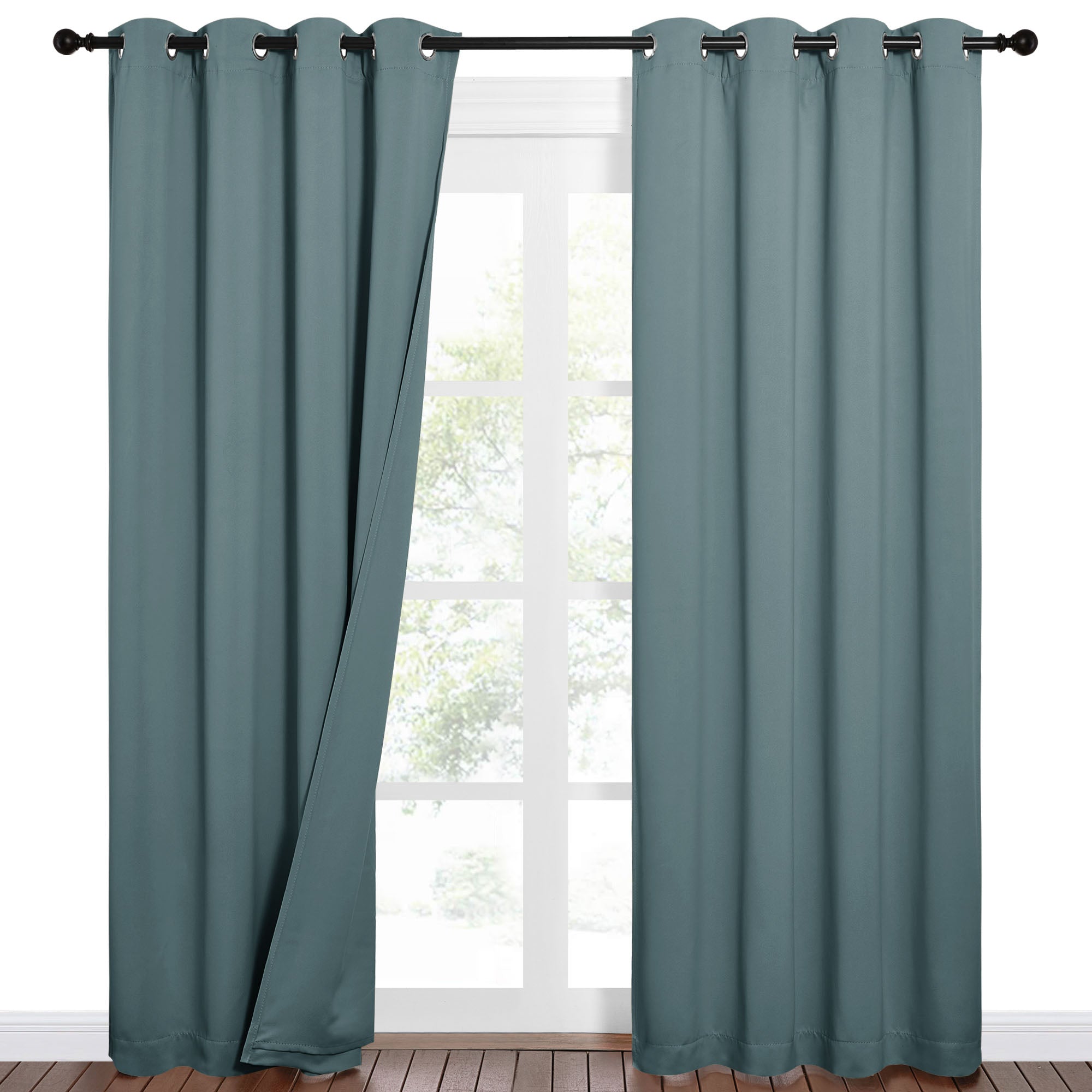 Teal grommet top Sound Barrier 100% blackout curtains, one panel open, hung on a black rod over a window.