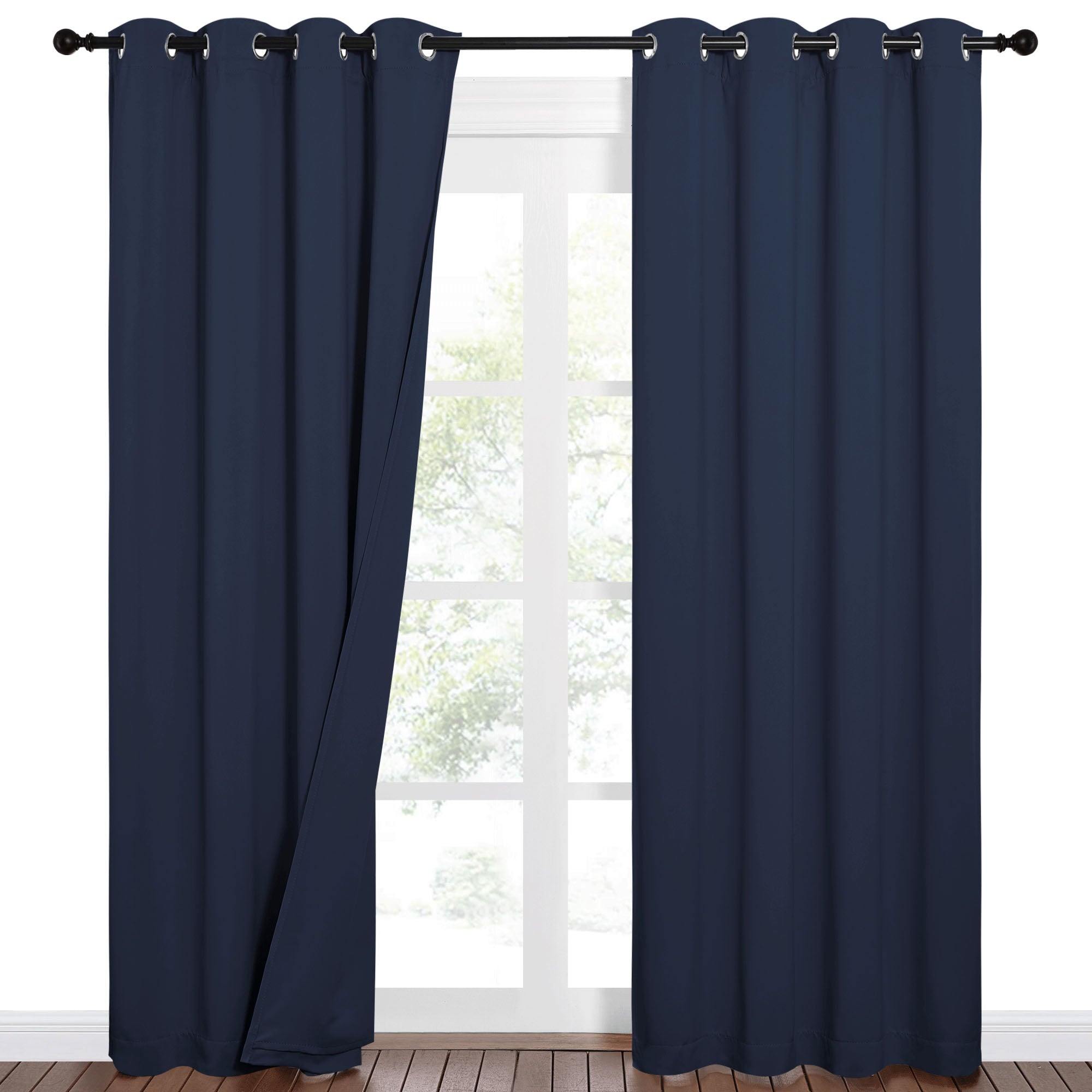 Navy blue grommet top blackout curtains hanging on a dark rod over a window, one panel slightly open.