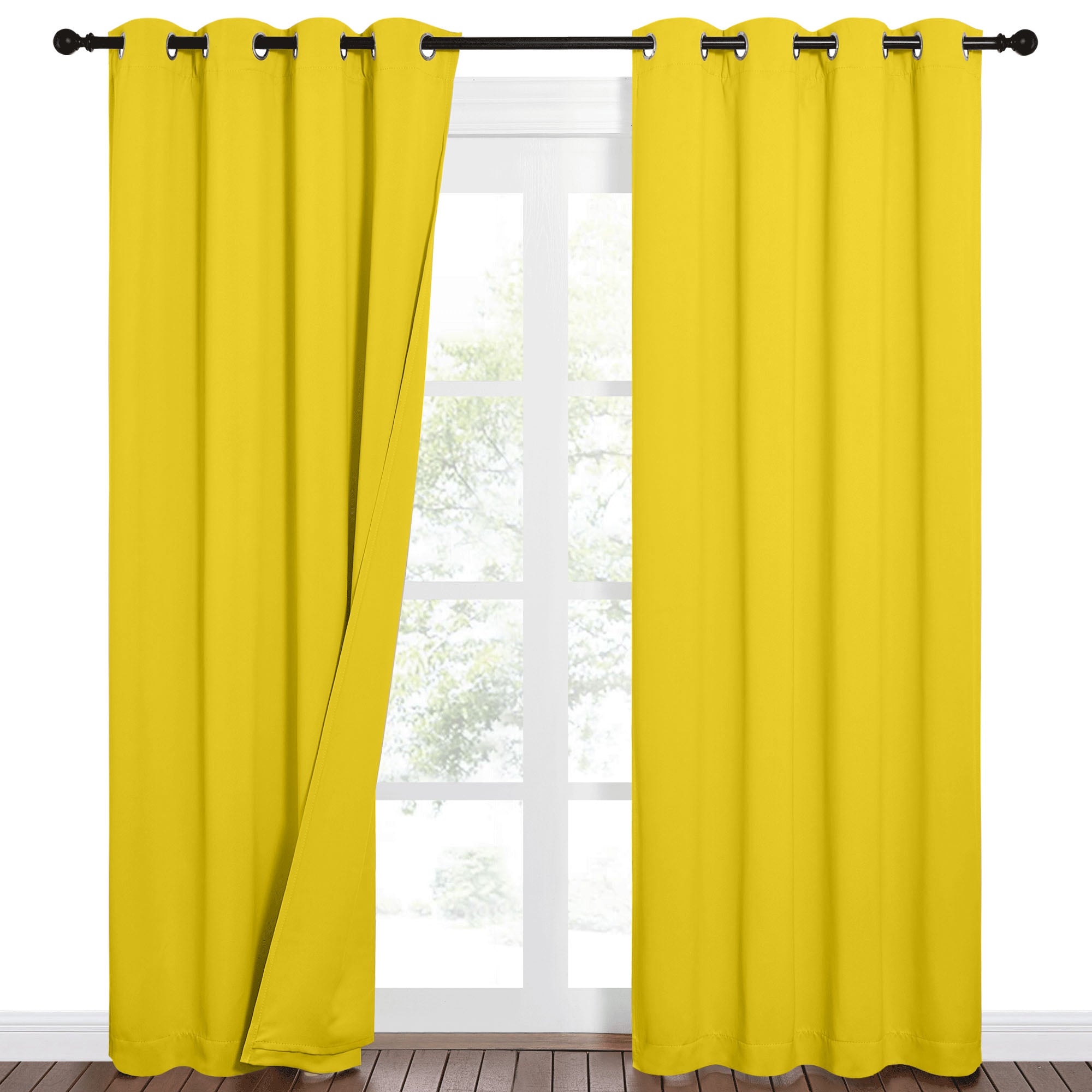 Vibrant yellow blackout curtains with grommet tops on a black rod, one partially open revealing a window with trees. Dark wood floor visible.