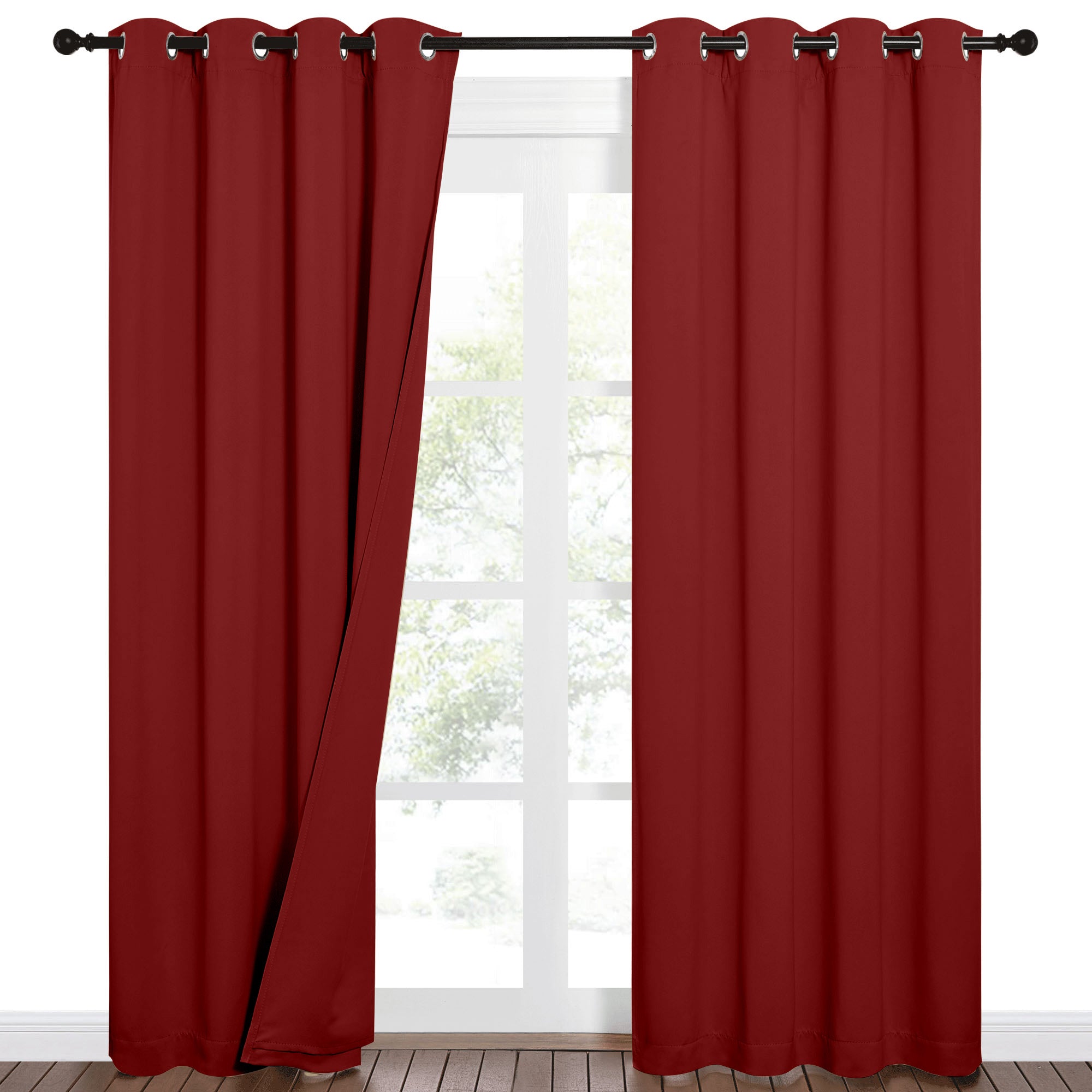 Deep red grommet blackout curtains on a rod, with one panel slightly open, revealing a window with trees outside.