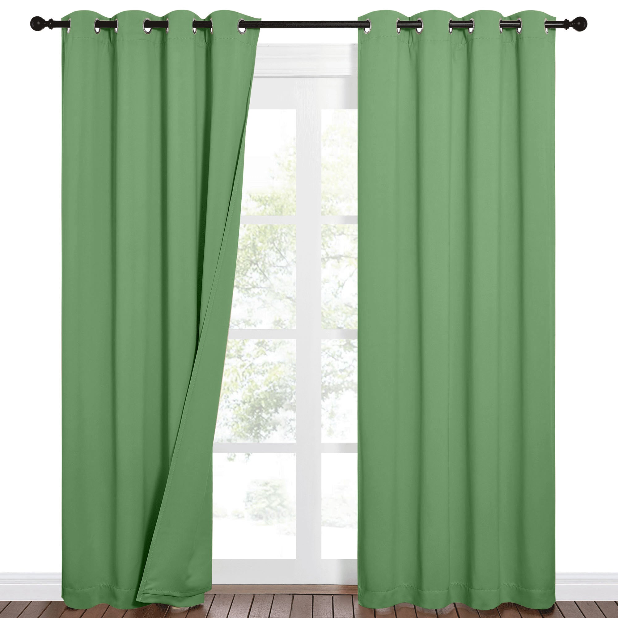 Sage green Sound Barrier 100% blackout curtains with grommet tops, one panel partially open at a window.