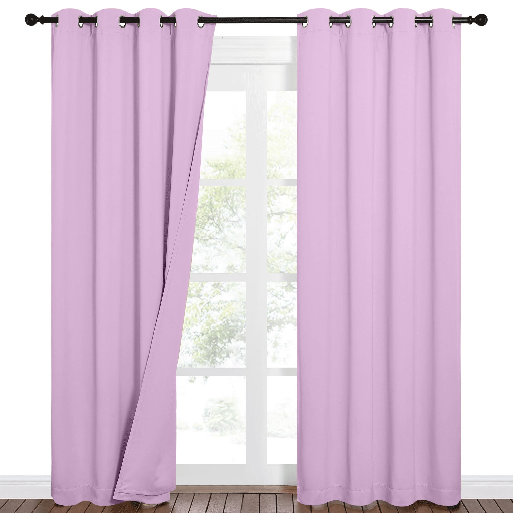 Lavender sound barrier blackout curtains with grommet tops, one panel slightly open on a black rod over a window.