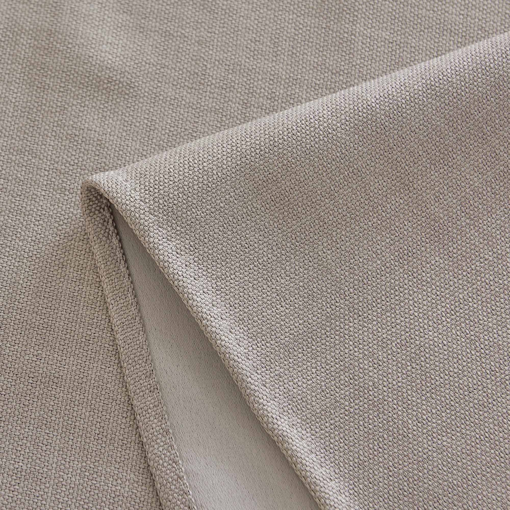 Close-up of a light brown woven tablecloth fabric, highlighting its textured material and neatly hemmed edge.