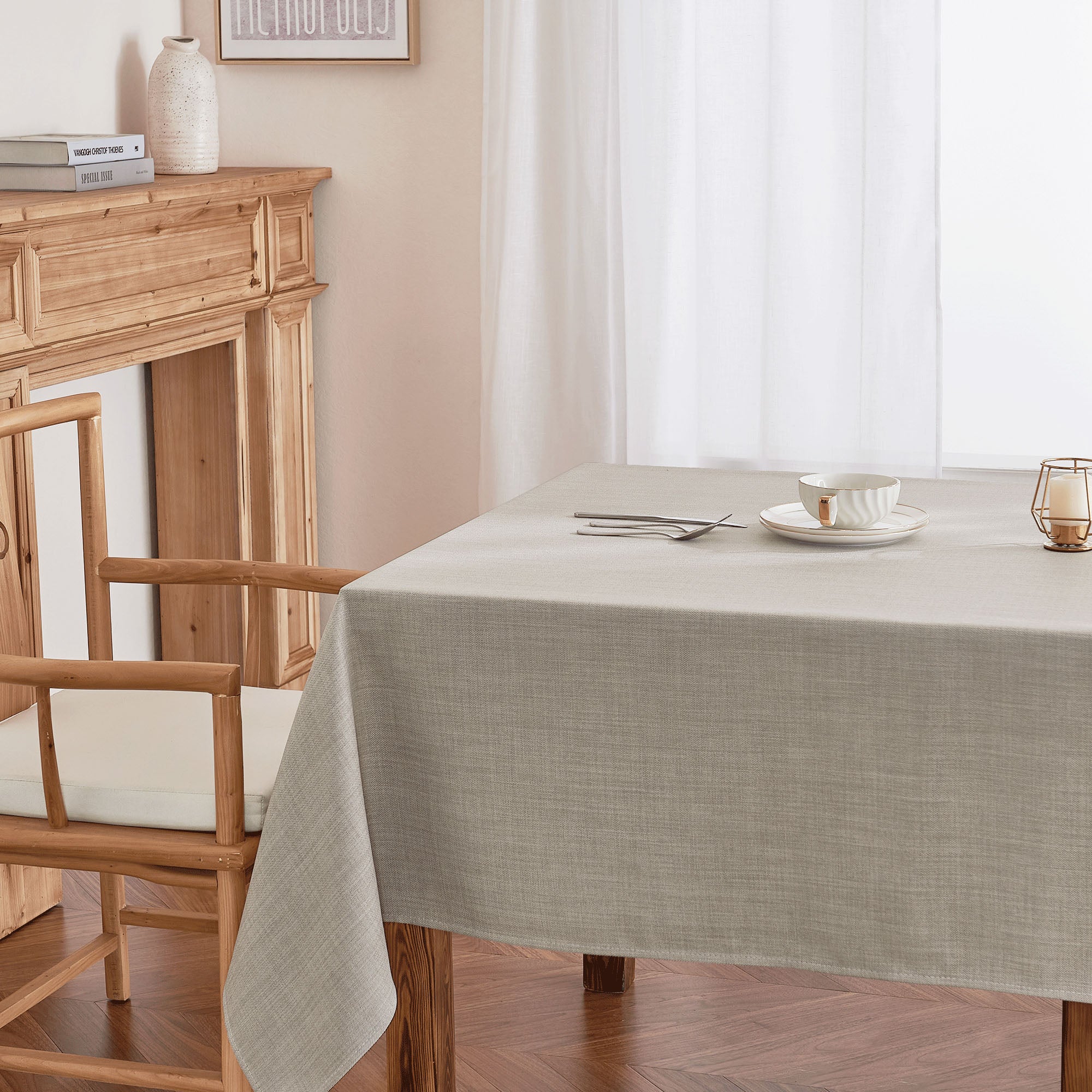 Beige linen texture tablecloth on a wooden dining table, set with dishes and a candle, enhancing home decor.