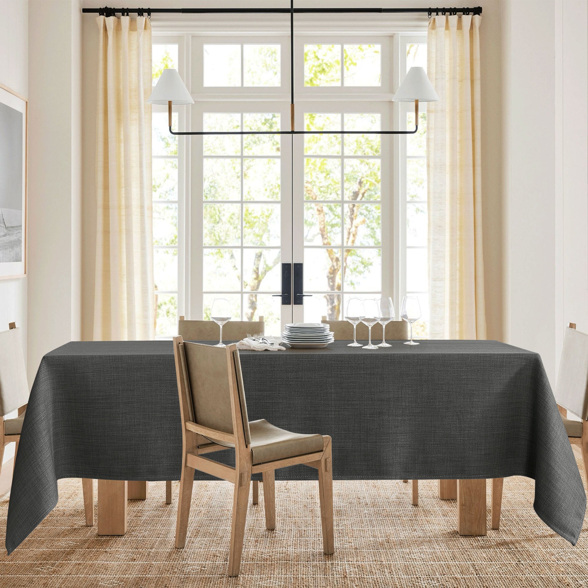 Elegant dark grey textured tablecloth draped over a dining table, styled with dinnerware and wine glasses in a bright room.