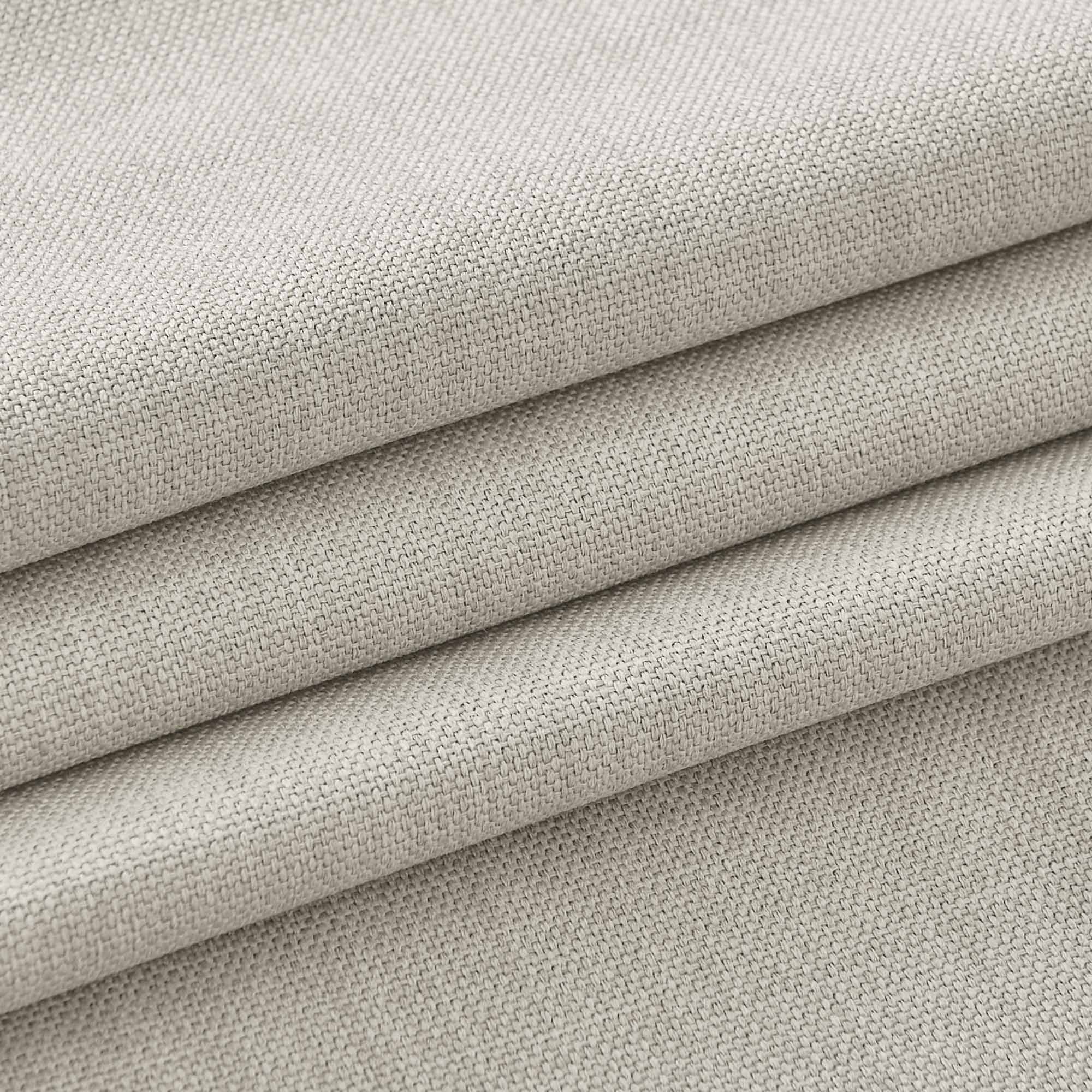 Close-up of a light beige textured tablecloth fabric, folded to reveal its detailed woven pattern and material.