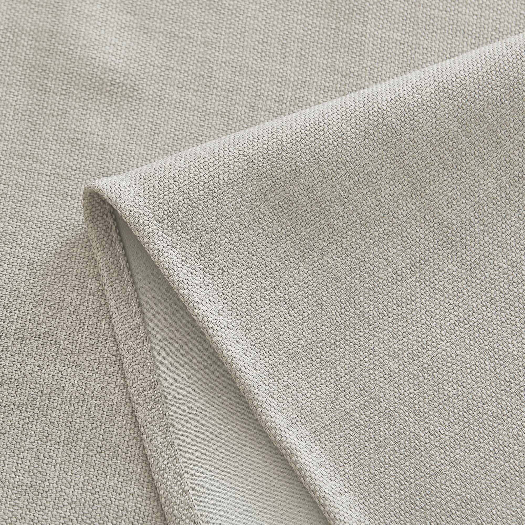 Close-up of light beige woven tablecloth fabric, highlighting its texture and neatly stitched hem.