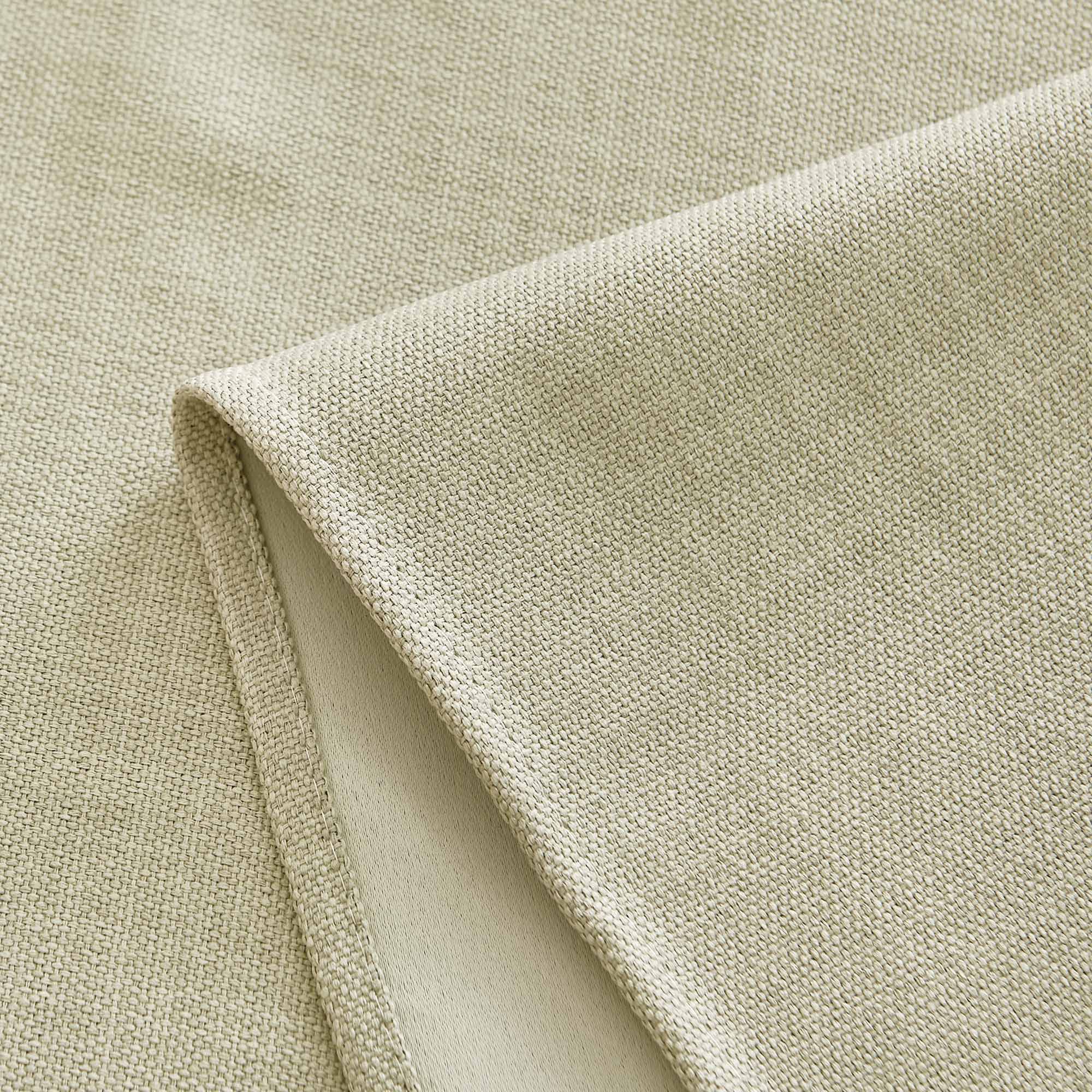 Close-up of light neutral woven tablecloth fabric detail, highlighting the visible texture and neatly stitched hem.