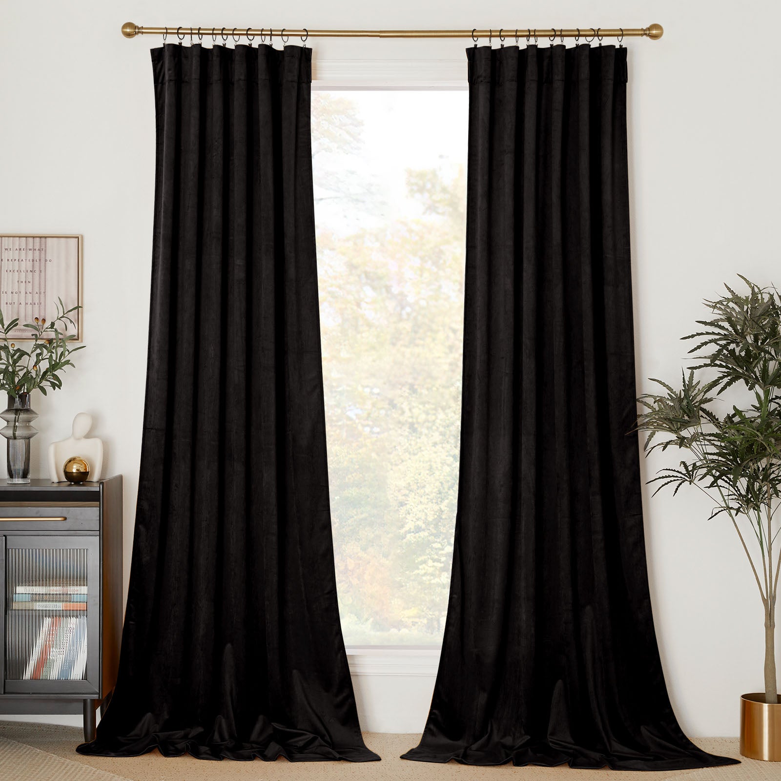 Two long black velvet curtain panels hanging on a gold rod, framing a tall window in a modern living room.