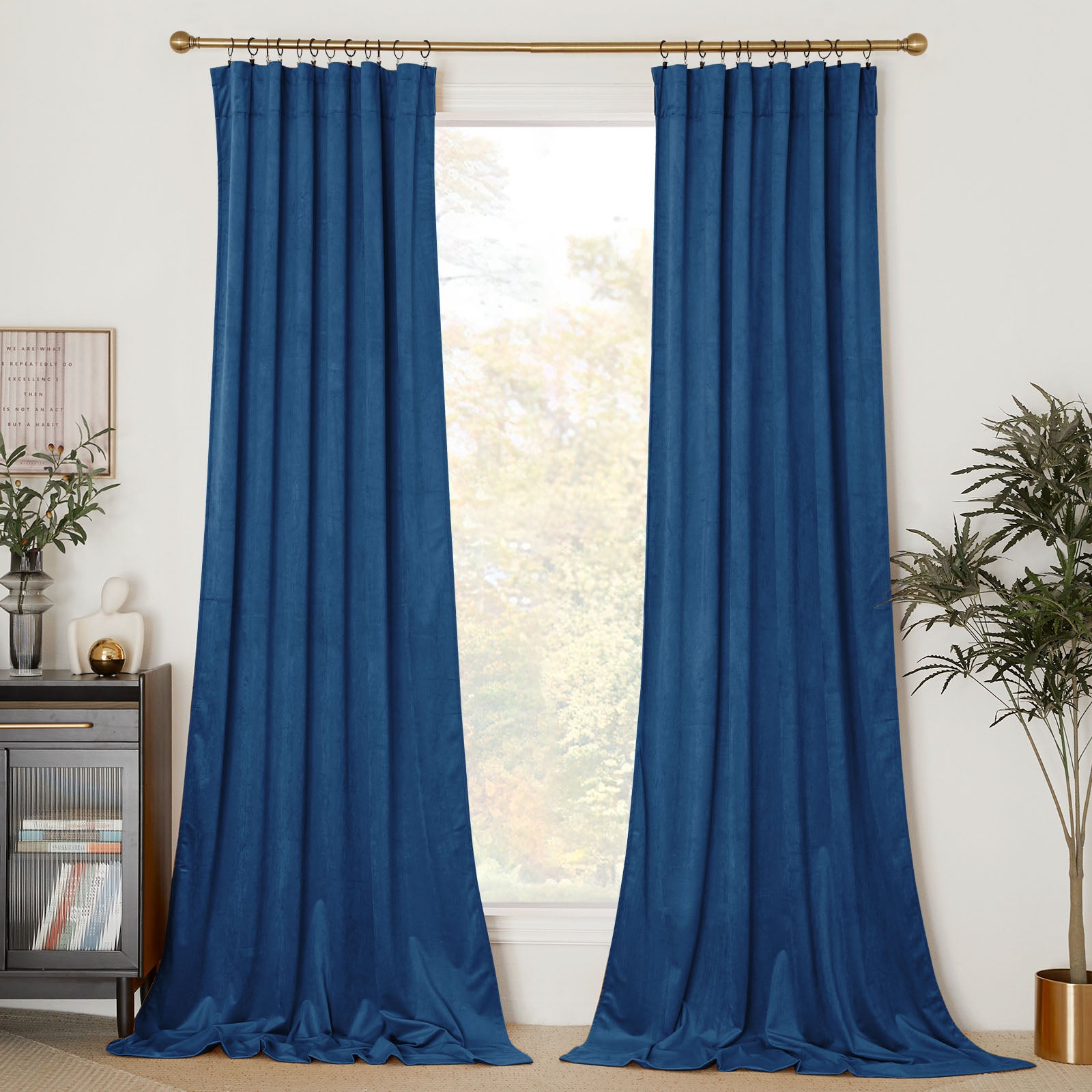 Full view of long blue velvet curtain panels hanging on a gold rod, framing a window and pooling elegantly on the floor.