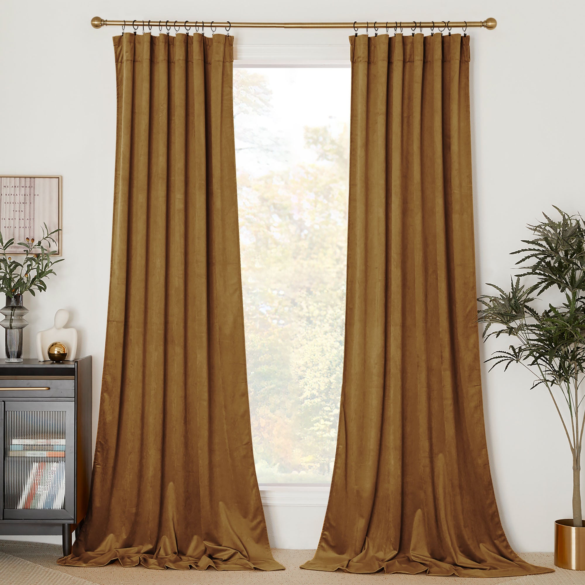 Long, golden-brown velvet curtain panels hang from a gold rod, framing a window and pooling elegantly on the floor.