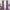 A pair of long, purple velvet curtains hanging on a gold rod, framing a tall window in a styled living room.