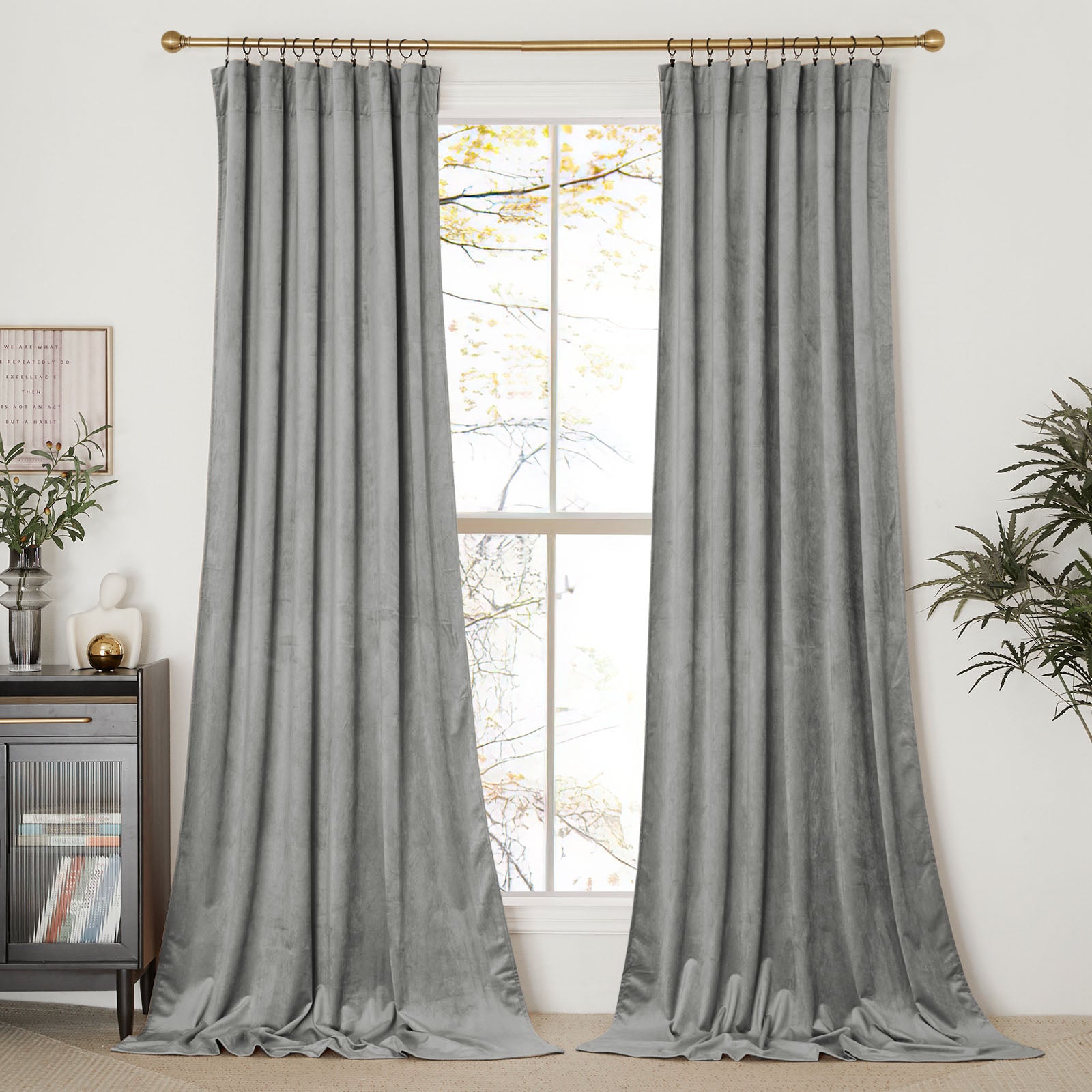 Full view of two floor-length grey velvet curtain panels hung on a gold rod, framing a window in a living room.