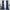 A pair of long, blue velvet curtain panels hanging on a gold curtain rod, framing a bright window in a styled room.