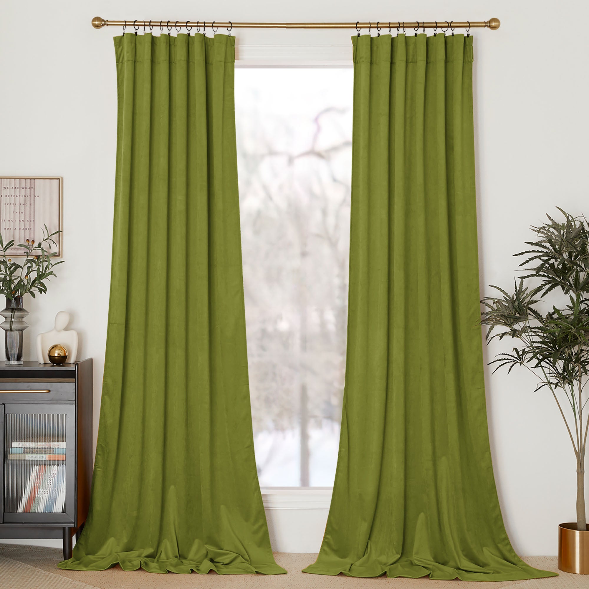 Full-length olive green velvet curtains hanging on a gold rod with rings, framing a window in a styled room.