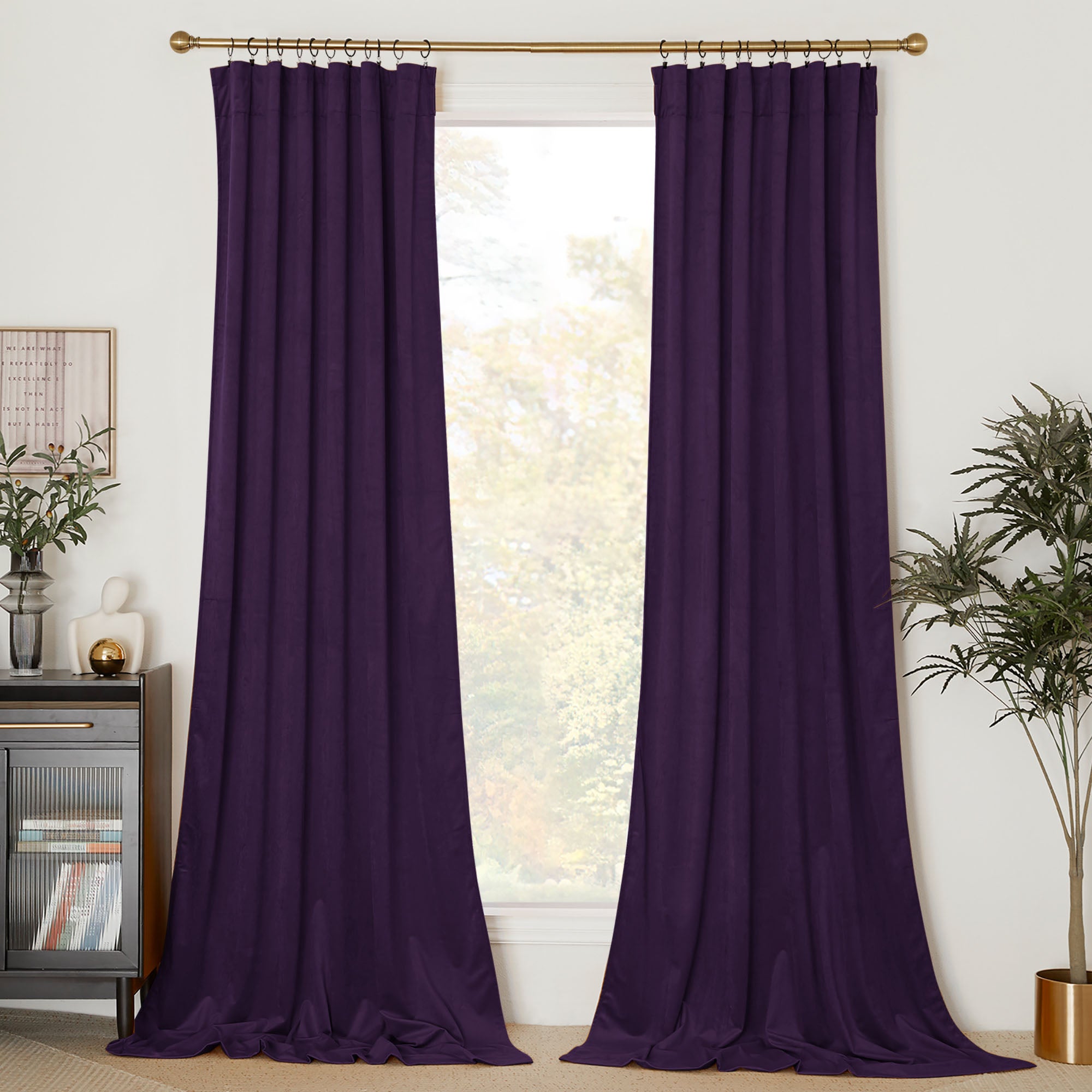 Two panels of long, dark purple velvet curtains hanging from a gold rod, framing a bright window in a modern living room.