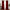 Full view of two rich red velvet curtains hanging from a gold rod, puddled on the floor and framing a tall window.