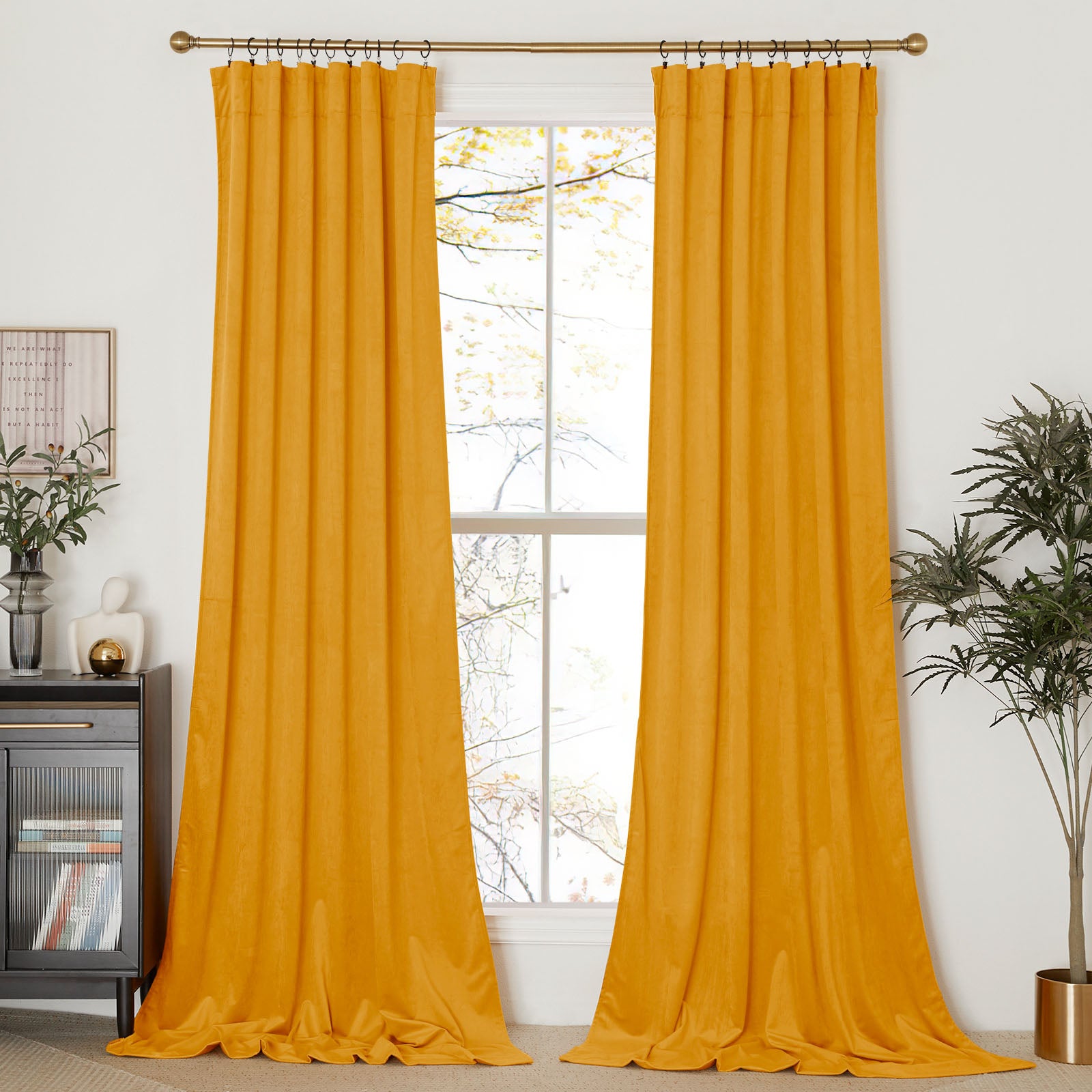 Long mustard velvet curtains hung with black rings on a gold rod, framing a window in a modern living room.