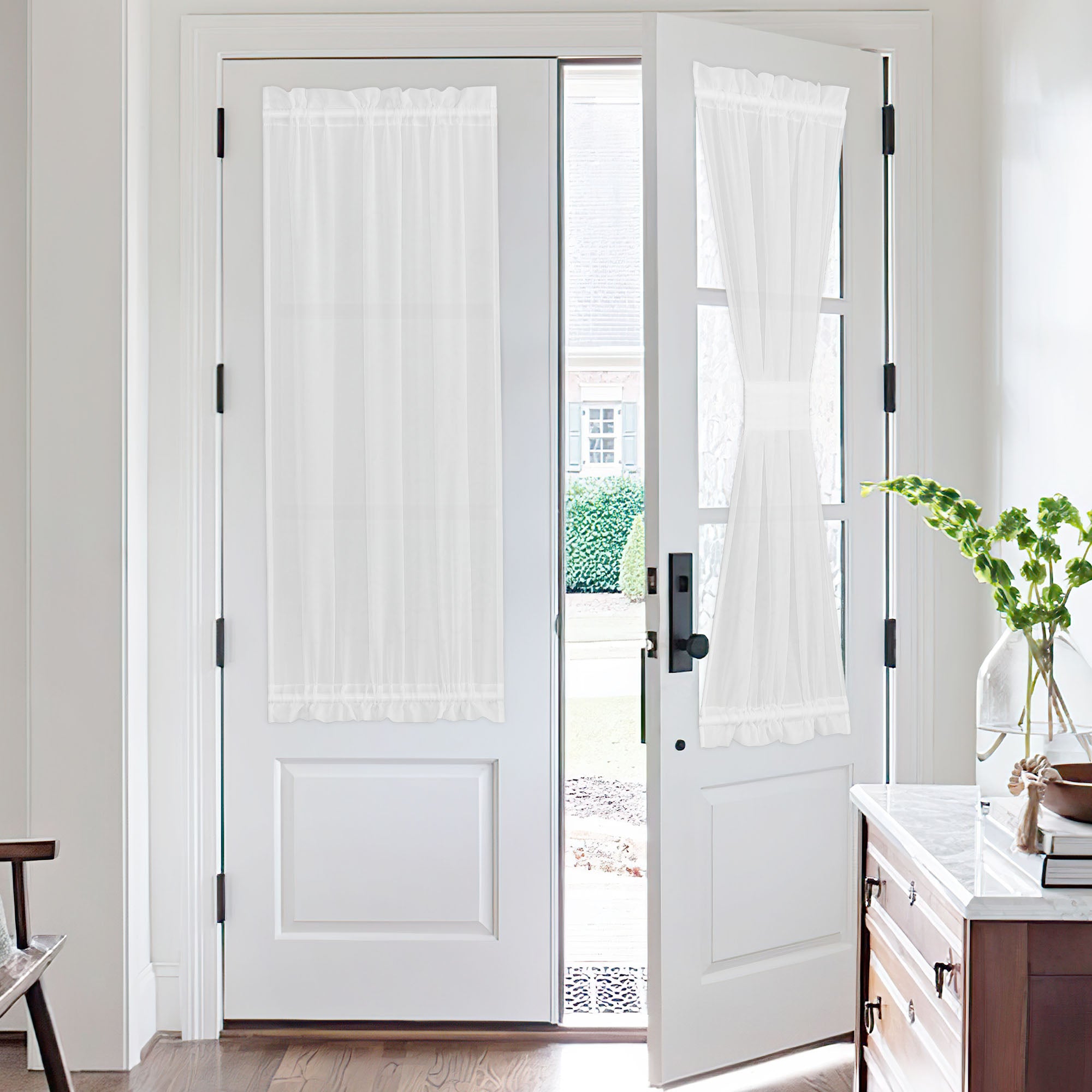 White voile sheer door curtains providing privacy and light filtering on two white French doors. One is full, the other tied back.
