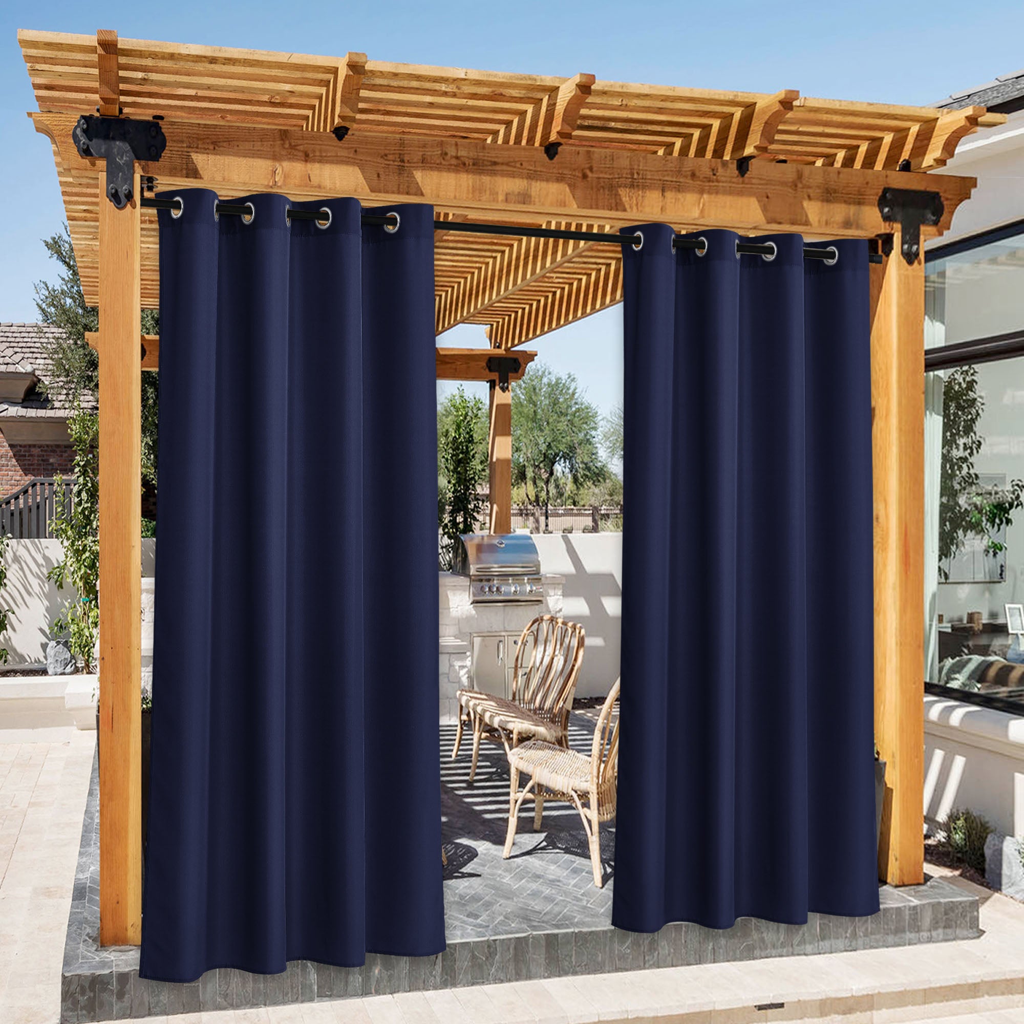 Navy blue waterproof canvas outdoor curtains with grommets on a wooden pergola, partially open revealing a patio BBQ area.