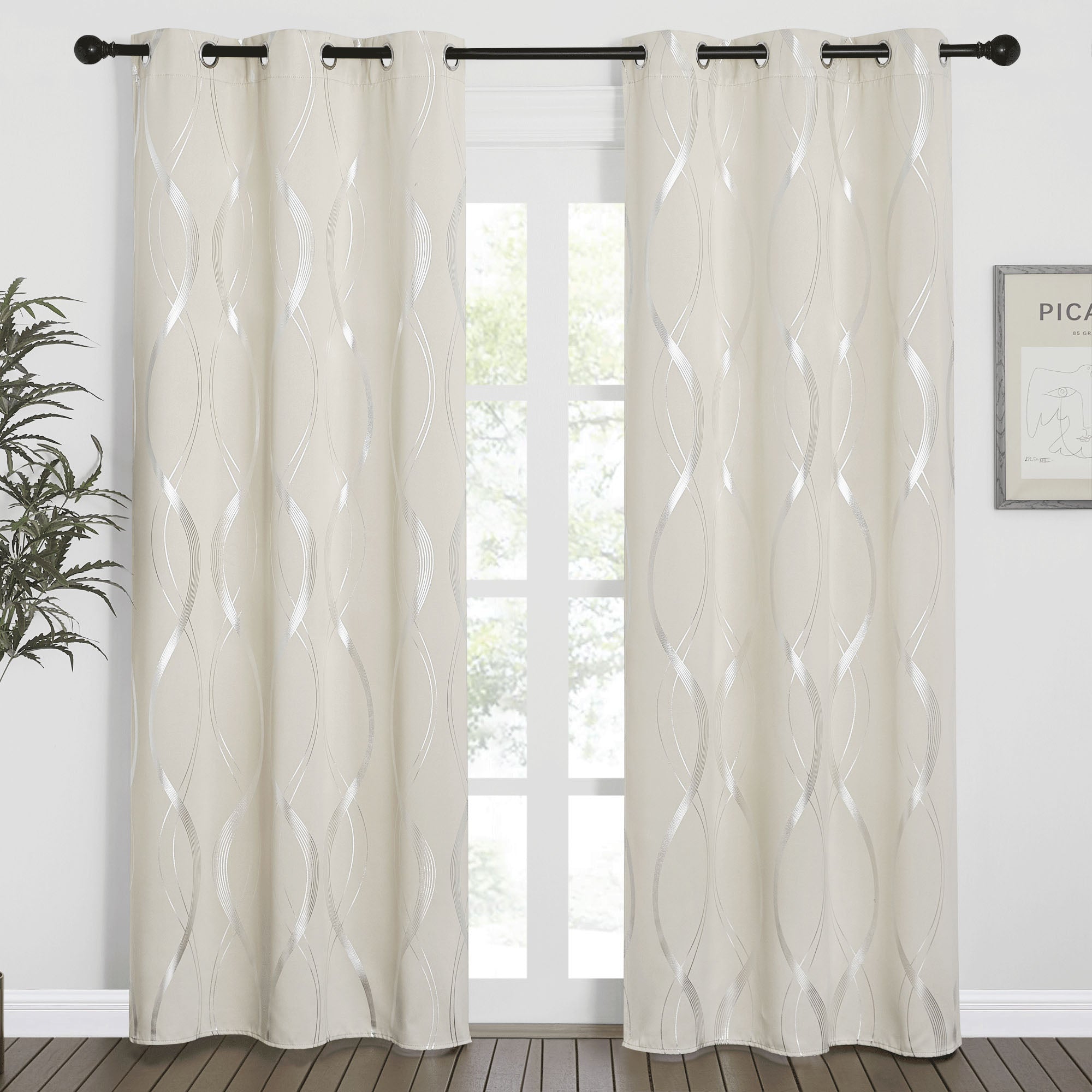 Cream wave line blackout curtains with silver pattern, grommet tops on a black rod, flanking a window with a view, wood floor, and room decor.