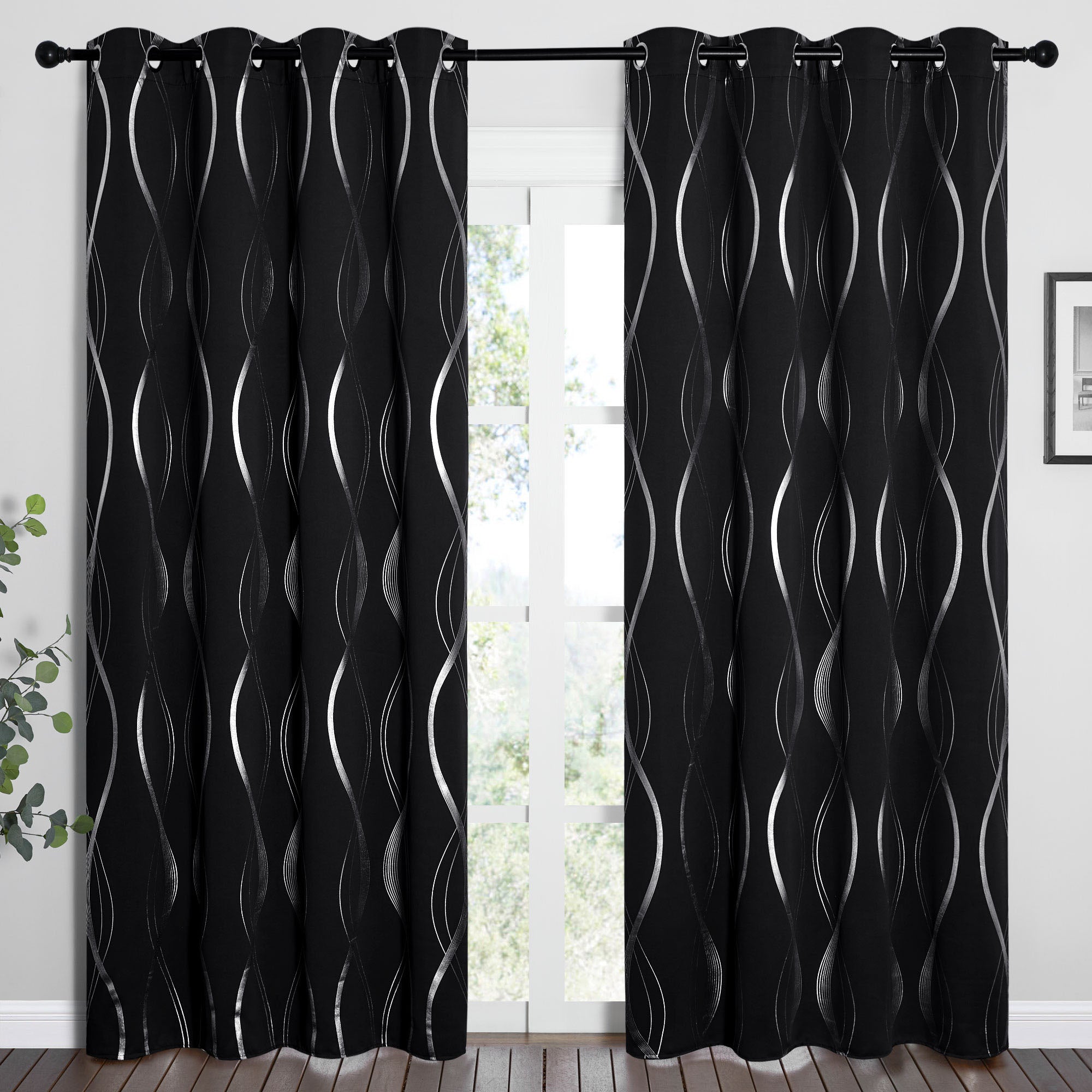 Modern black blackout curtains with silver wave line pattern and grommet tops, hanging on a window rod.