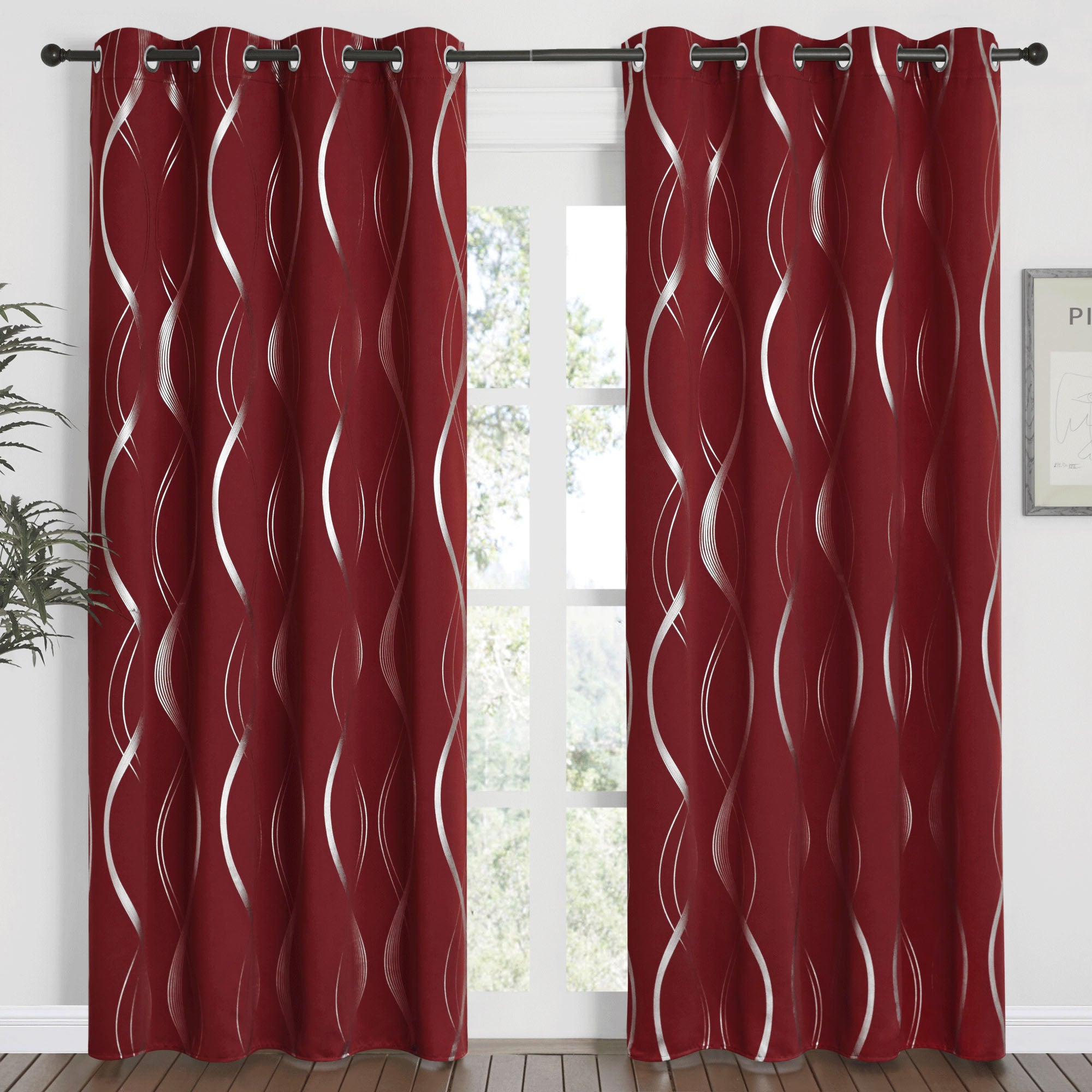 Deep red blackout curtains with a bold silver wave line pattern, hung from grommets on a dark rod, covering a bright window.