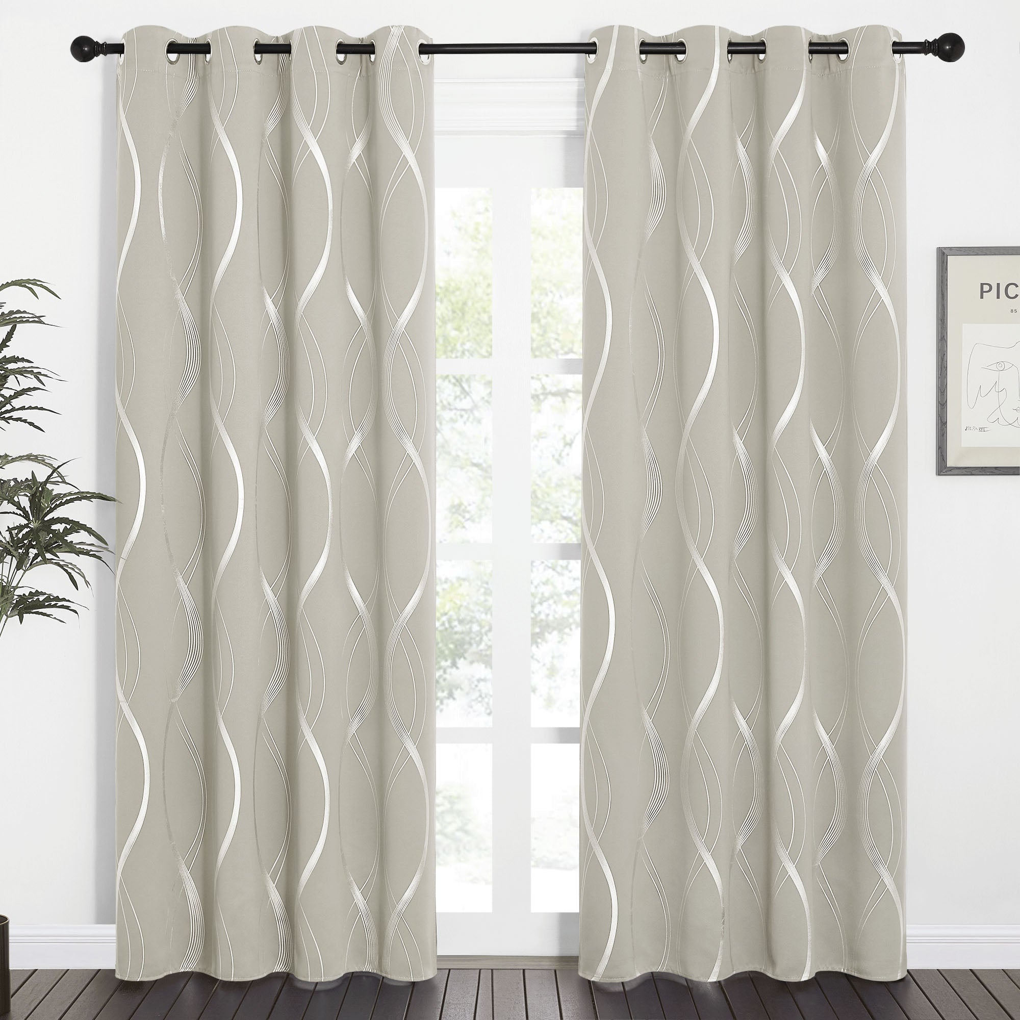 Pair of light grey wave line blackout curtains with metallic silver patterns & grommet tops, hung on a black rod over a window.
