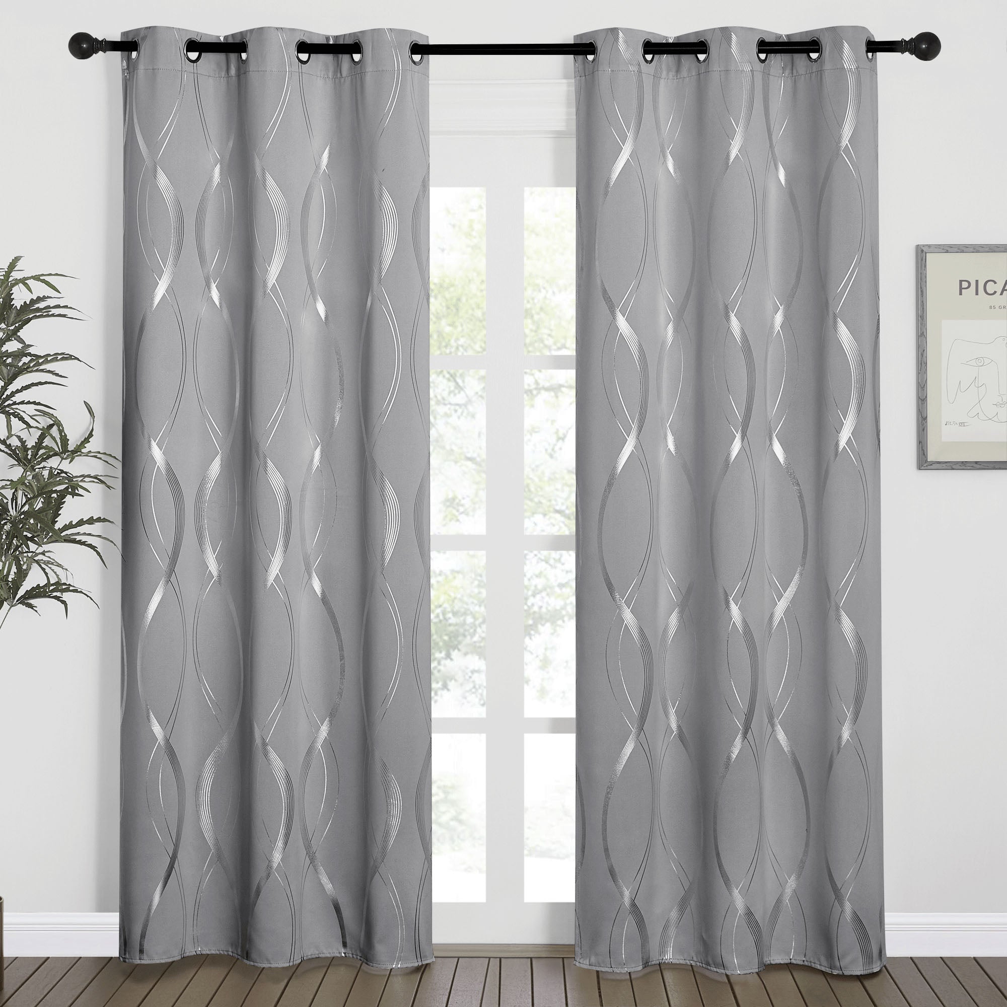 Pair of grey blackout curtains with silver wave-line pattern and grommet top, hanging on a black rod in front of a window.