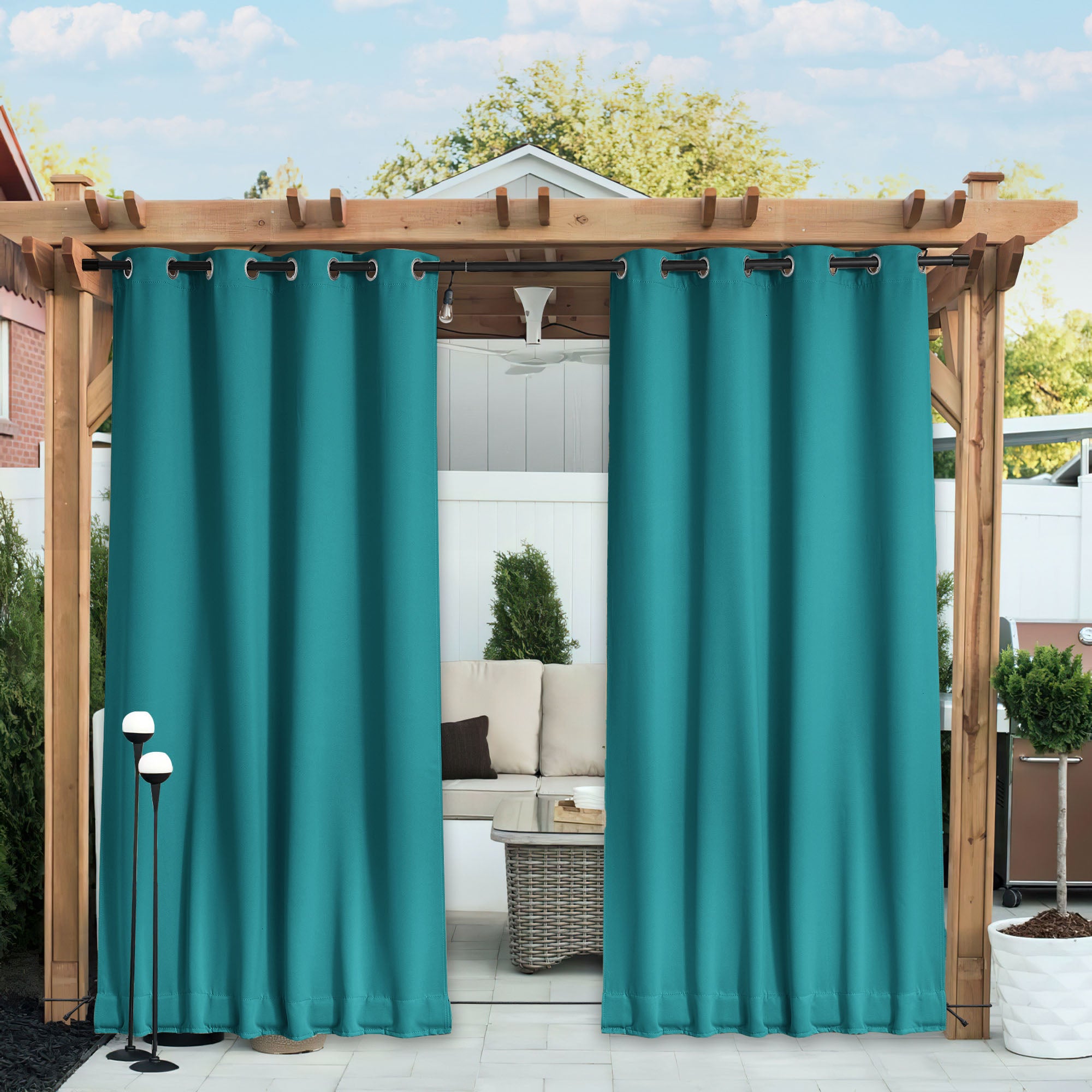 Turquoise waterproof blackout outdoor curtains hanging on a wooden pergola, partially open to a patio seating area.