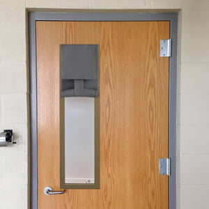 Adjustable charcoal grey fabric door window cover partially rolled up on a light brown wooden door.