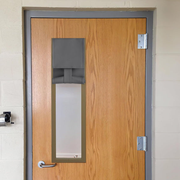 Adjustable charcoal grey fabric door window cover partially rolled up on a light brown wooden door.