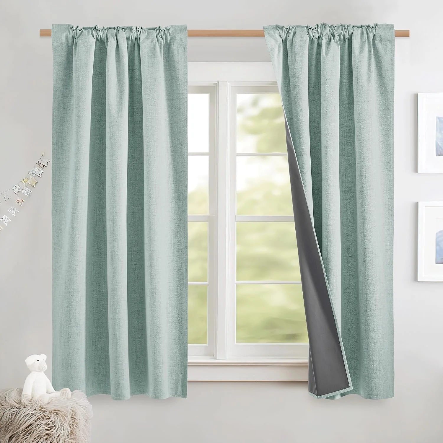 Light aqua blackout curtains with textured fabric on a wooden rod by a bright window