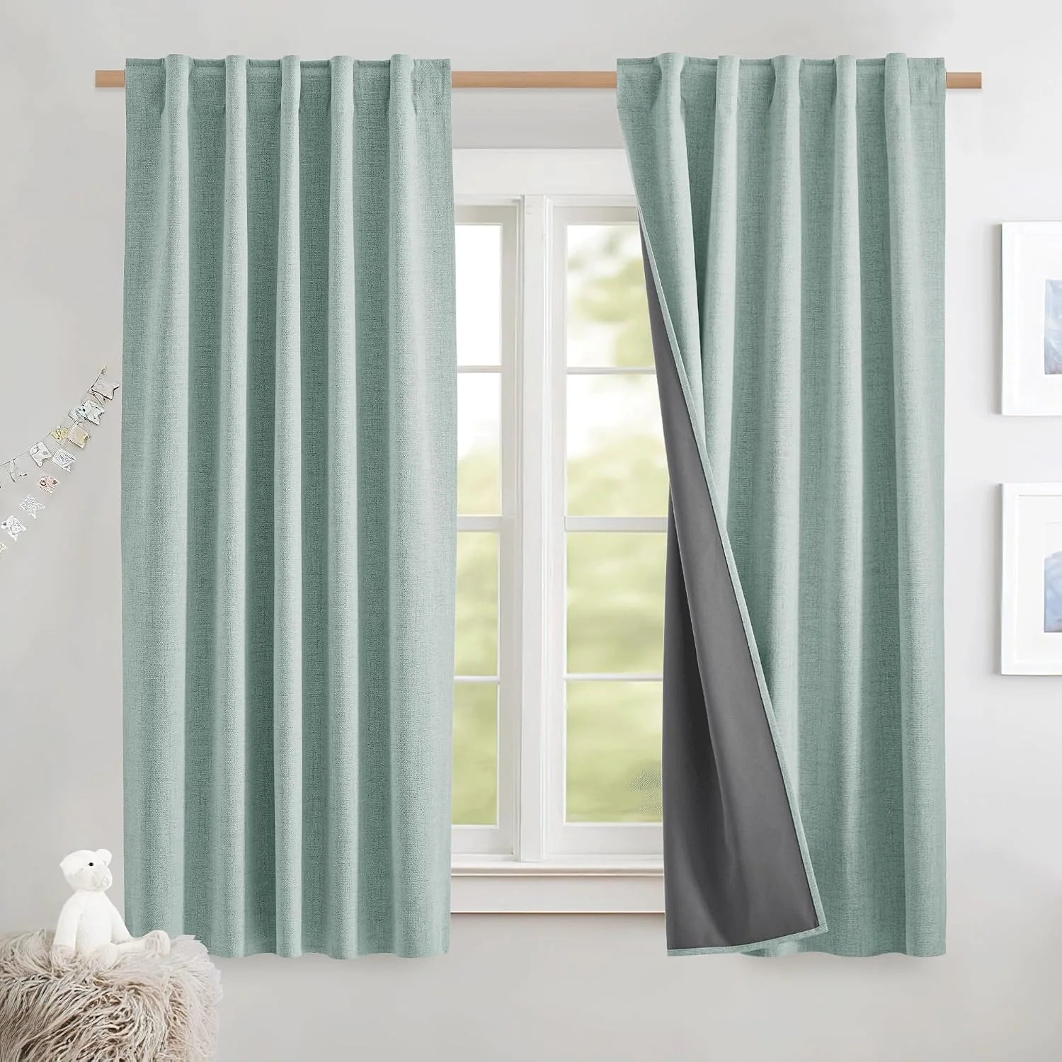 Light aqua textured blackout curtains on a wooden rod in a bright kids room window