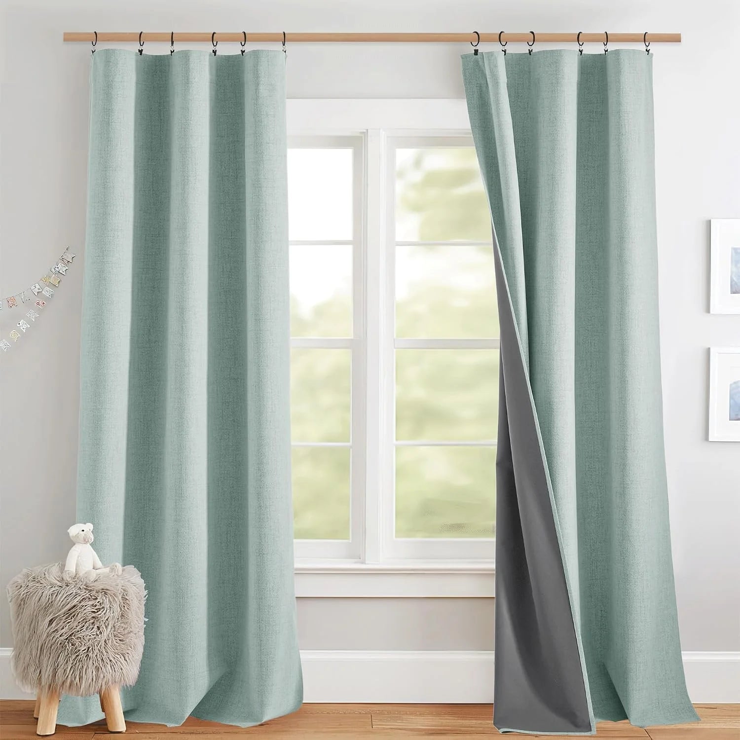 Aqua textured blackout curtains with black liner hanging on rings in a bright room