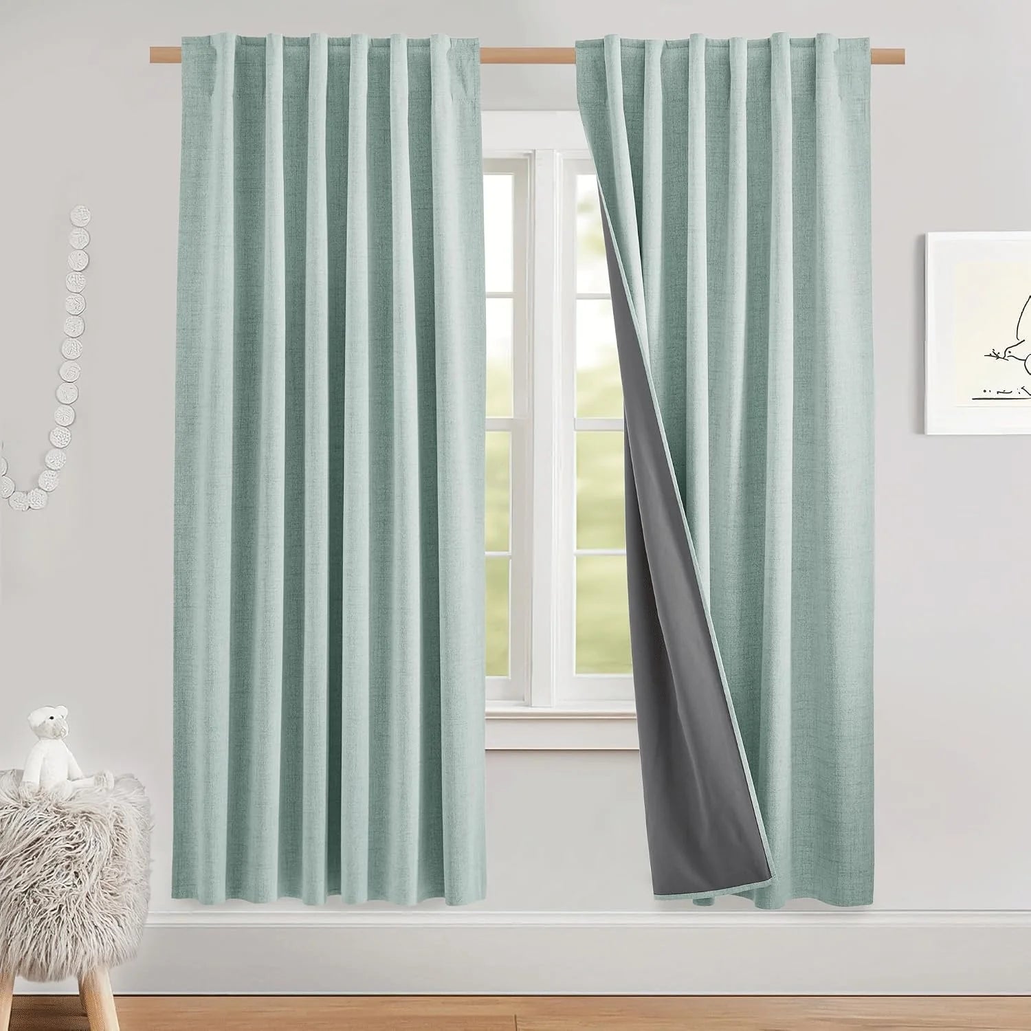 Light aqua textured blackout curtains with gray lining hanging on a wood rod