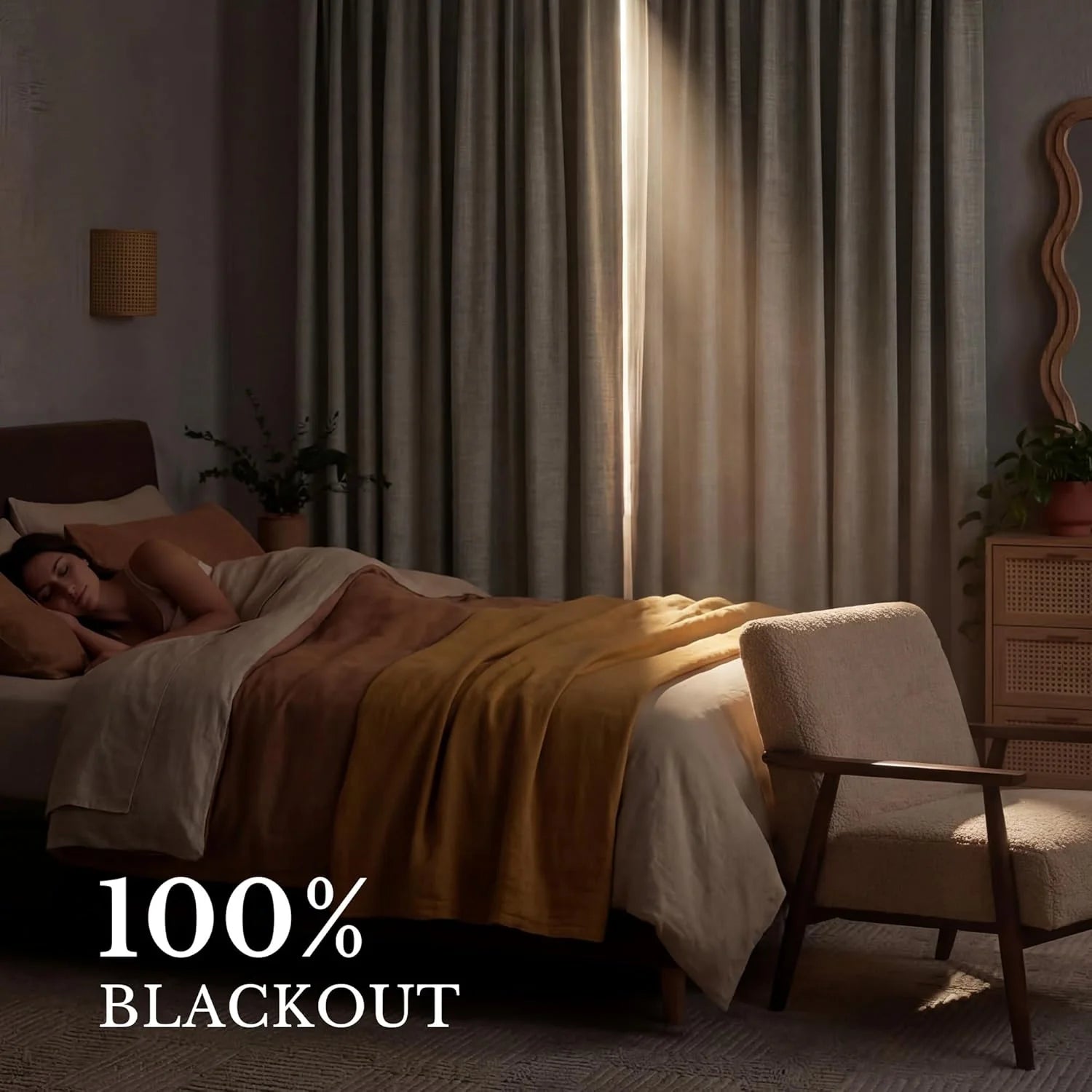 Woman sleeping soundly in a dark bedroom with light gray blackout curtains.