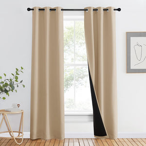 Beige blackout curtain panels with visible black lining and metal grommet top hanging on a rod.