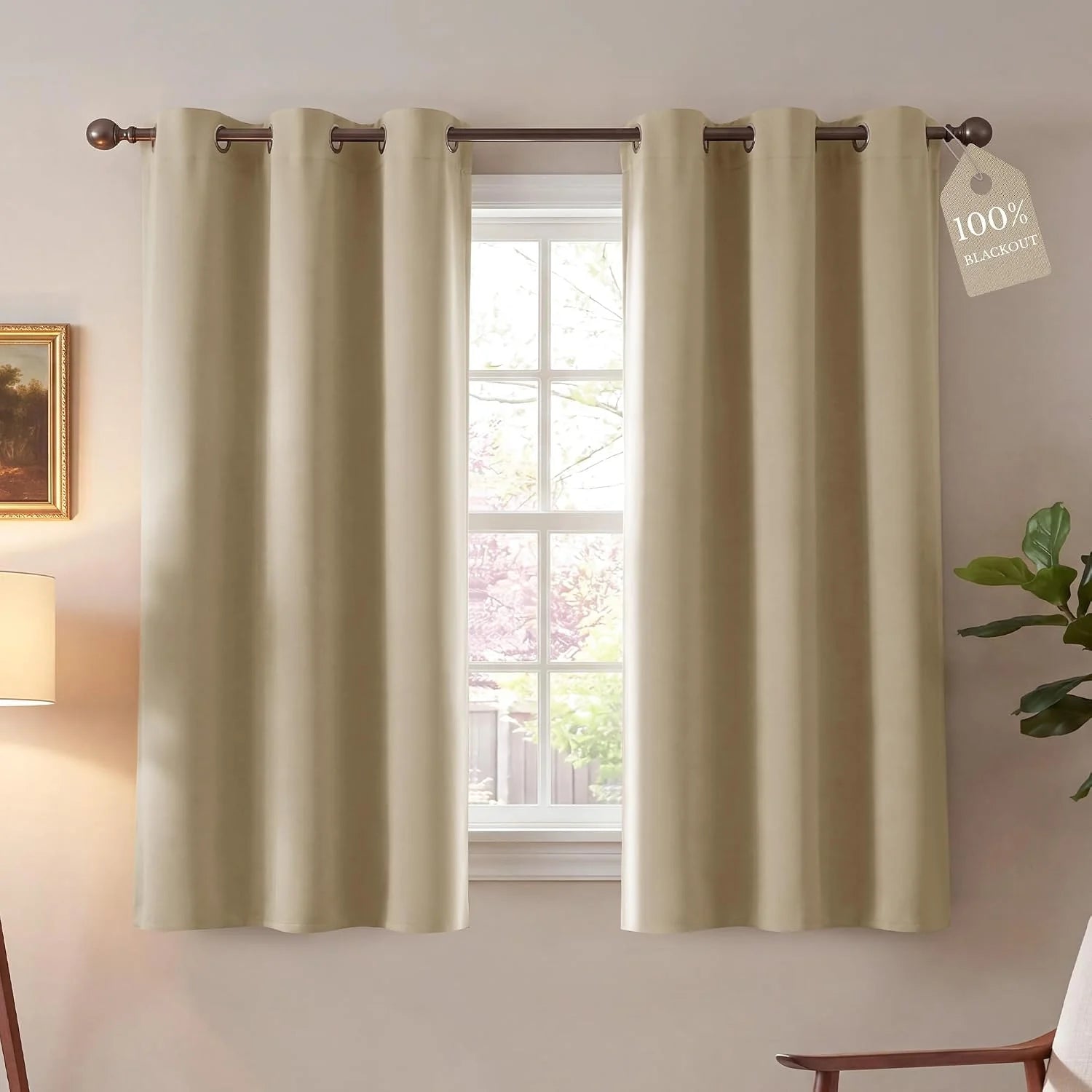 Pair of beige blackout curtains with bronze grommet tops on a bright window