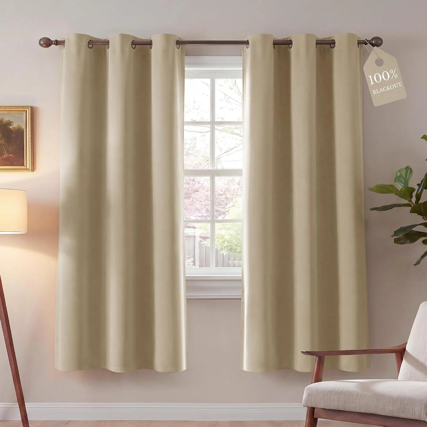 Pair of beige 100% blackout grommet curtains hanging in a bright room.