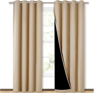 Beige blackout curtains with silver grommet tops hanging on a rod, one panel showing its black lining.