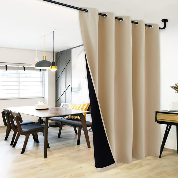 Beige thermal blackout grommet curtain with black lining, dividing a modern dining space.