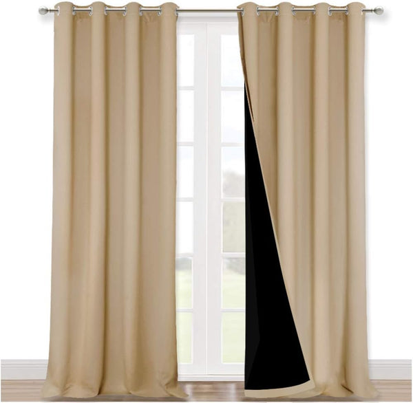 Pair of beige blackout curtains with silver grommets hang on a rod, showing dark lining.