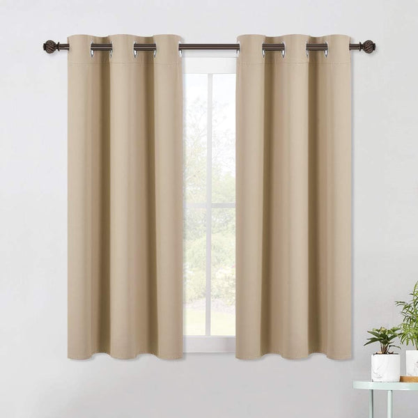 Solid beige blackout curtains with silver grommet tops hang on a dark bronze rod over a window.