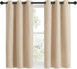 Two beige solid blackout curtain panels with black grommet tops on a dark rod.