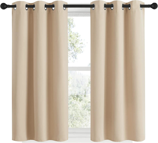 Two beige solid blackout curtain panels with black grommet tops on a dark rod.